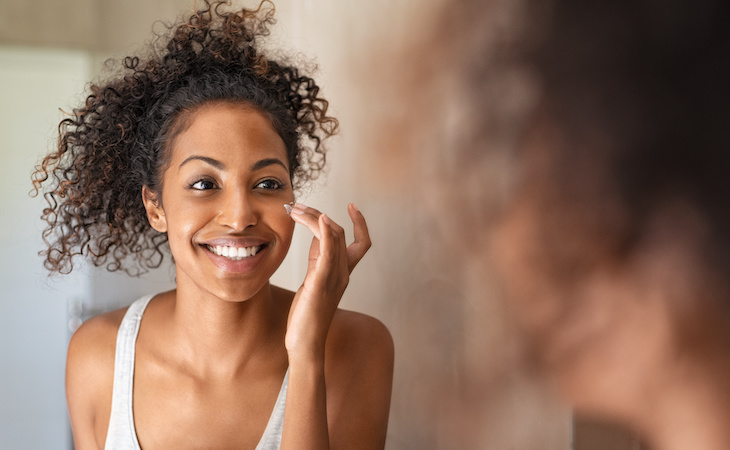 person applying melatonin skincare product to face