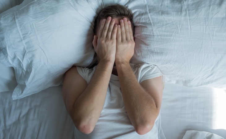 Person covering face in bed